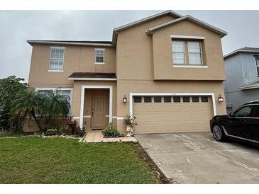 Charming two-story home featuring neutral stucco, a two-car garage, and a well-manicured front lawn at 2480 Brownwood Dr, Mulberry, FL 33860