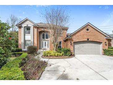 Charming two-story brick home with an attached garage, manicured landscaping and concrete driveway at 5406 Baytowne Place, Oviedo, FL 32765