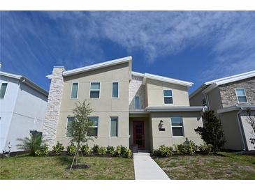 Charming modern home featuring a red front door, stone accents, and landscaped front yard at 2956 Penelope Loop, Kissimmee, FL 34746