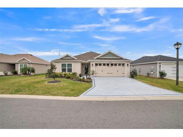 Beautiful home with a well-manicured lawn, stylish driveway, and an attached two-car garage under a sunny sky at 6922 Wendy Way, The Villages, FL 34762