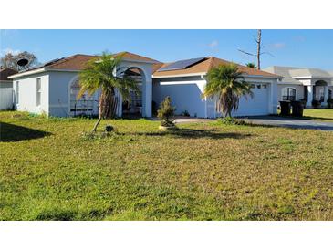Charming home featuring a well-maintained lawn and mature palm trees, with solar panels discreetly installed at 661 Crane Dr, Kissimmee, FL 34759