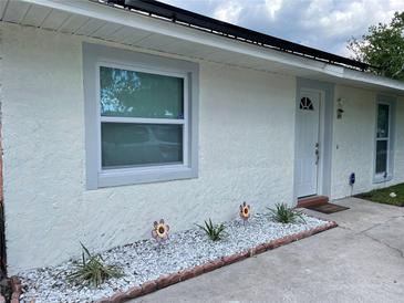 Charming home featuring a stucco exterior, white trim, decorative rocks, and solar panels at 5977 Wallace Dr, Orlando, FL 32807