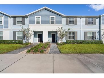 Charming townhome with a blue exterior, well-manicured lawn, and inviting walkway at 627 Jasmine Ln, Davenport, FL 33897