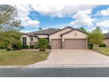 Stunning single-story home with a well-manicured lawn, paver driveway, and a two-car garage at 9761 Sw 74Th Pl, Ocala, FL 34481