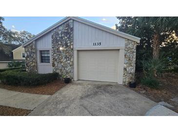 Charming exterior elevation featuring a one-car garage and stone accents on the front of the home at 1135 Linkside Ct, Apopka, FL 32712