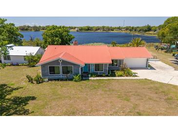 Charming waterfront home featuring a bright red roof and beautifully landscaped front yard overlooking the lake at 5020 Old Lucerne Park Rd, Winter Haven, FL 33881