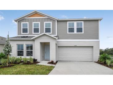 Charming two-story home with light gray siding, a well-manicured lawn, and an attached two-car garage at 1014 Foreshore Ln, Haines City, FL 33844