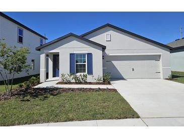 Charming single-Gathering home with a freshly landscaped yard, an attached two-car garage and dark blue door and shutters at 1649 Nantucket Way, Winter Haven, FL 33884