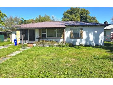 Front exterior of home with metal roof, overgrown foliage and unkempt lawn at 1122 E Edgewood Dr, Lakeland, FL 33803