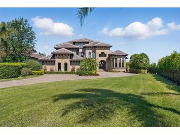 Stunning stone and stucco home with a manicured lawn, lush landscaping, and a paver driveway on a sunny day at 7769 Summerlake Pointe Blvd, Winter Garden, FL 34787