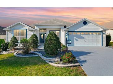 Charming single-story home featuring a well-manicured lawn, two-car garage, and beautiful landscaping at 2518 Foxbridge Ter, The Villages, FL 32162