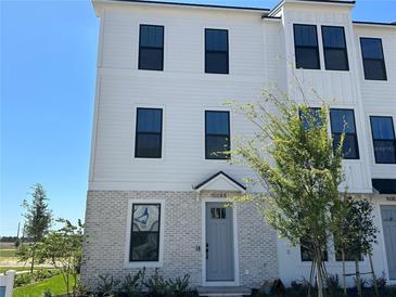 Charming three-story townhouse featuring light gray brickwork and a light gray front door at 15088 Grove Lake Dr, Winter Garden, FL 34787