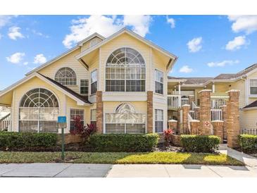 Condominium exterior featuring large windows, brick columns, and manicured landscaping, creating an inviting entrance at 5012 Laguna Bay Cir # 72, Kissimmee, FL 34746