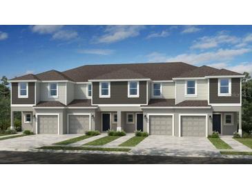 Beautiful exterior of new townhomes featuring attached garages, covered entryways and neutral-toned siding under a blue sky at 7605 Waterscape Dr, Groveland, FL 34736