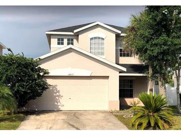 Two-story home featuring an attached two-car garage and mature landscaping at 14417 Jasmine Glen Dr, Orlando, FL 32824