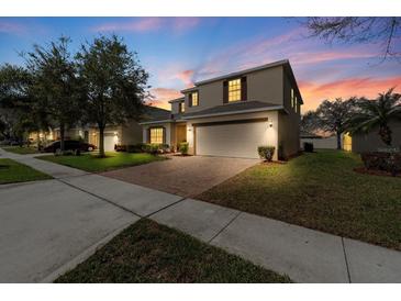 Charming two-story home with a brick paver driveway, manicured lawn, and attached two-car garage at 754 Andalusia Loop, Davenport, FL 33837