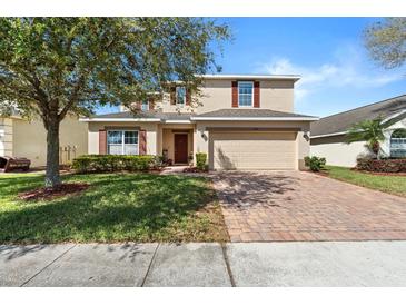 Charming two-story home featuring a well-manicured lawn, brick driveway, and a welcoming two-car garage at 754 Andalusia Loop, Davenport, FL 33837