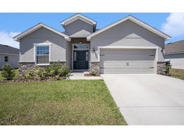 Charming single-story home with gray stucco, stone accents, a two-car garage and well-manicured lawn at 7066 Victoria Rd, Lakeland, FL 33809