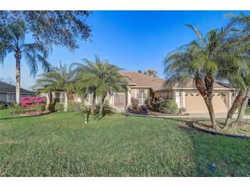 Charming single-story home featuring a well-manicured lawn and mature palm trees at 10837 Versailles Blvd, Clermont, FL 34711