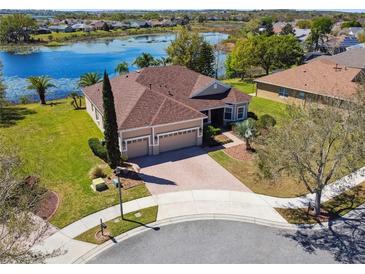 Beautiful lakefront home featuring a three-car garage, brick driveway, and meticulously landscaped yard at 252 Bayou Bend Rd, Groveland, FL 34736