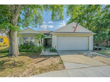 Charming single-story home featuring an attached garage, mature trees, and appealing landscaping at 6125 Morningdale Ave, Lakeland, FL 33813