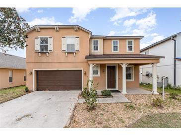 Two-story home with a well-maintained yard, covered entrance, and a two-car garage at 265 Elderberry Dr, Davenport, FL 33897