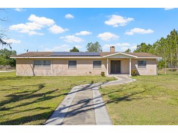 Charming single-story brick home featuring a well-manicured lawn and solar panels at 4305 Hamilton Rd, Lakeland, FL 33811