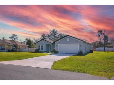 Charming single-story home featuring a well-manicured lawn and a two-car garage against a vibrant sky at 2840 Sw 166 Th Ln, Ocala, FL 34473
