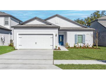 Beautiful single-story home featuring a well-manicured lawn, a two-car garage, and a charming blue front door at 13284 Tula Loop, Astatula, FL 34705
