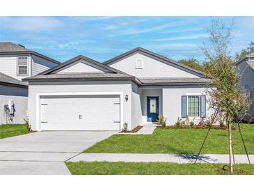 Charming single-story home featuring a two-car garage, manicured lawn, and welcoming blue front door at 13442 Leaping Water Way, Astatula, FL 34705
