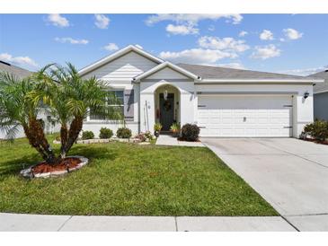 Charming single-story home with well-maintained lawn, landscaping, and an attached two-car garage on a sunny day at 879 Killarney Ln, Auburndale, FL 33823