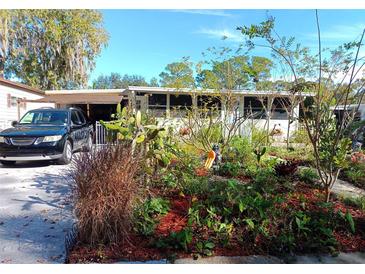 Charming home exterior featuring a beautiful front yard garden and a car parked in the carport at 109 Fern Dr, Debary, FL 32713