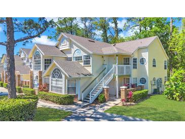 Charming two-story condo featuring a well-manicured lawn and delightful, sun-kissed yellow siding at 5005 Laguna Bay Cir # 18, Kissimmee, FL 34746