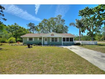 Charming single-story home with a well-maintained front lawn, mature trees, and a welcoming entrance at 2971 Gardenia Dr, Indian Lake Estates, FL 33855