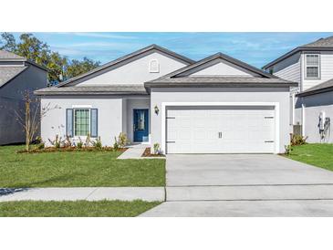 Charming single-Gathering home with a well-maintained lawn, blue door, and two-car garage at 13279 Tula Loop, Astatula, FL 34705