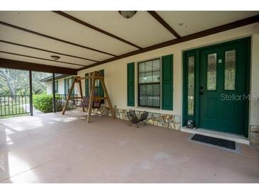 Spacious covered porch with a swing and decorative stone accents at 4586 Cr 696, Webster, FL 33597