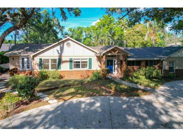 Charming home featuring a brick facade, lush landscaping, a blue front door, and a circular driveway at 1905 Seminole Trl, Lakeland, FL 33803