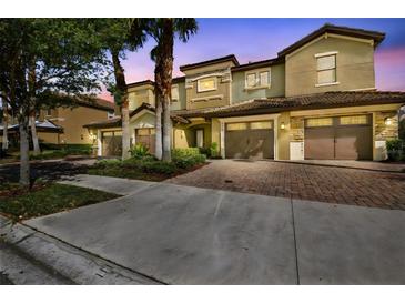 Townhome exterior showing covered garages, tropical landscaping, and multi-tone facade at 8983 Azalea Sands Ln # 8983, Davenport, FL 33896