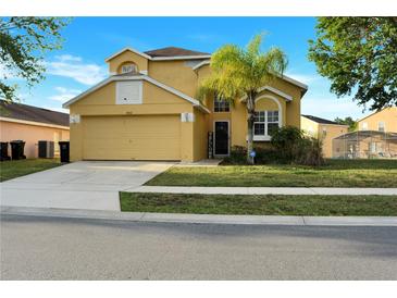 Charming yellow two-story home with a well-manicured lawn and attached two-car garage at 1802 Royal Ridge Dr, Davenport, FL 33896