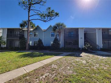 Charming condo building with blue siding, palm trees, and well-maintained landscaping under a clear blue sky at 3700 Idlebrook Cir # 206, Casselberry, FL 32707