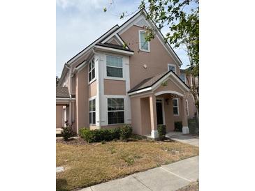 Charming two-story home featuring an arched entrance and freshly landscaped front yard at 3337 Soho St # 103, Orlando, FL 32835