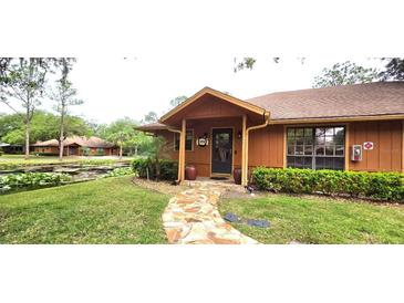 Quaint exterior view featuring lush landscaping, stone walkway, and inviting front porch at 472 Blue Heron Cir, River Ranch, FL 33867
