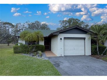 Charming single-story home featuring an attached one car garage, tropical landscaping and manicured lawn at 23 Buck Cir, Haines City, FL 33844