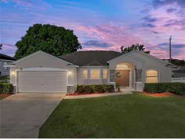 Charming home featuring manicured lawn, stone accents, and an attached two-car garage at twilight at 6272 Cornerstone Dr, Lakeland, FL 33813