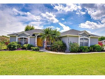 Charming one-story home with a well-manicured lawn, mature trees and inviting yellow front door at 3518 Remington Oaks Way, Lakeland, FL 33810