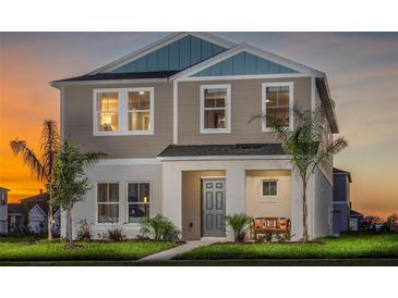 Charming two-story home featuring a covered front porch and manicured lawn at sunset at 2004 Marigold Aly, Winter Haven, FL 33884