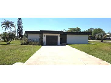 Charming single-story home with a well-manicured lawn and a long driveway leading to an attached garage at 25322 Columbia Cir, Lake Wales, FL 33898