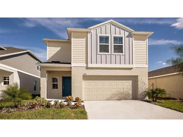 Charming two-story home with neutral siding, a blue front door, and an attached two-car garage at 4075 Gardenia Ave, Lake Hamilton, FL 33851