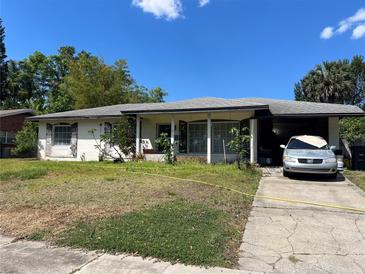 Modest single-story home with mature trees and a covered carport, presenting an opportunity for renovation at 617 Vandenberg St, Altamonte Springs, FL 32701