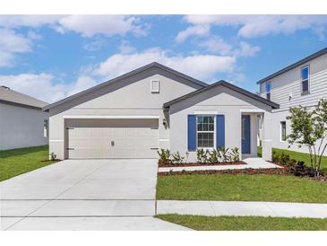 Charming single-story home with a two-car garage, blue accents, and well-manicured landscaping at 1794 White Elephant Loop, Winter Haven, FL 33884